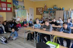 Dzieci siedzą w ławkach.